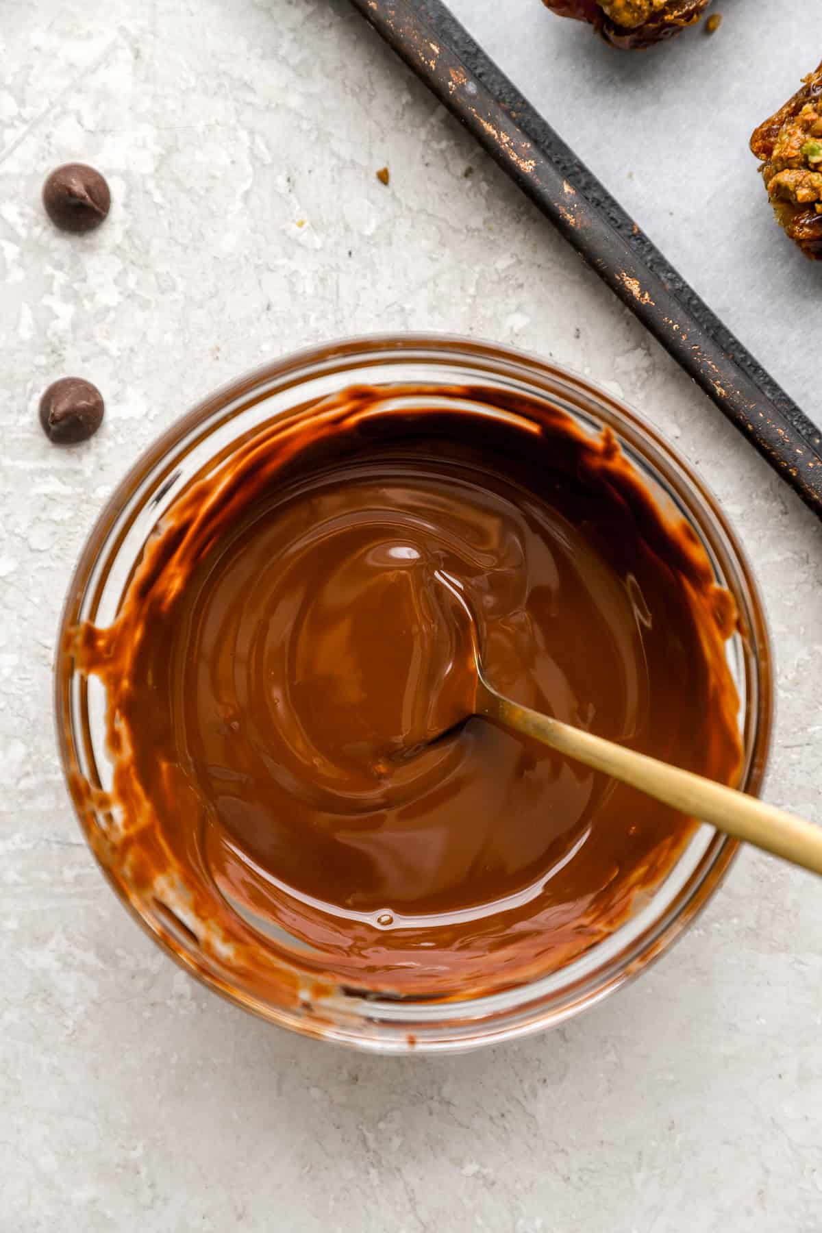 Melted chocolate in a bowl with a wooden spoon sticking out.