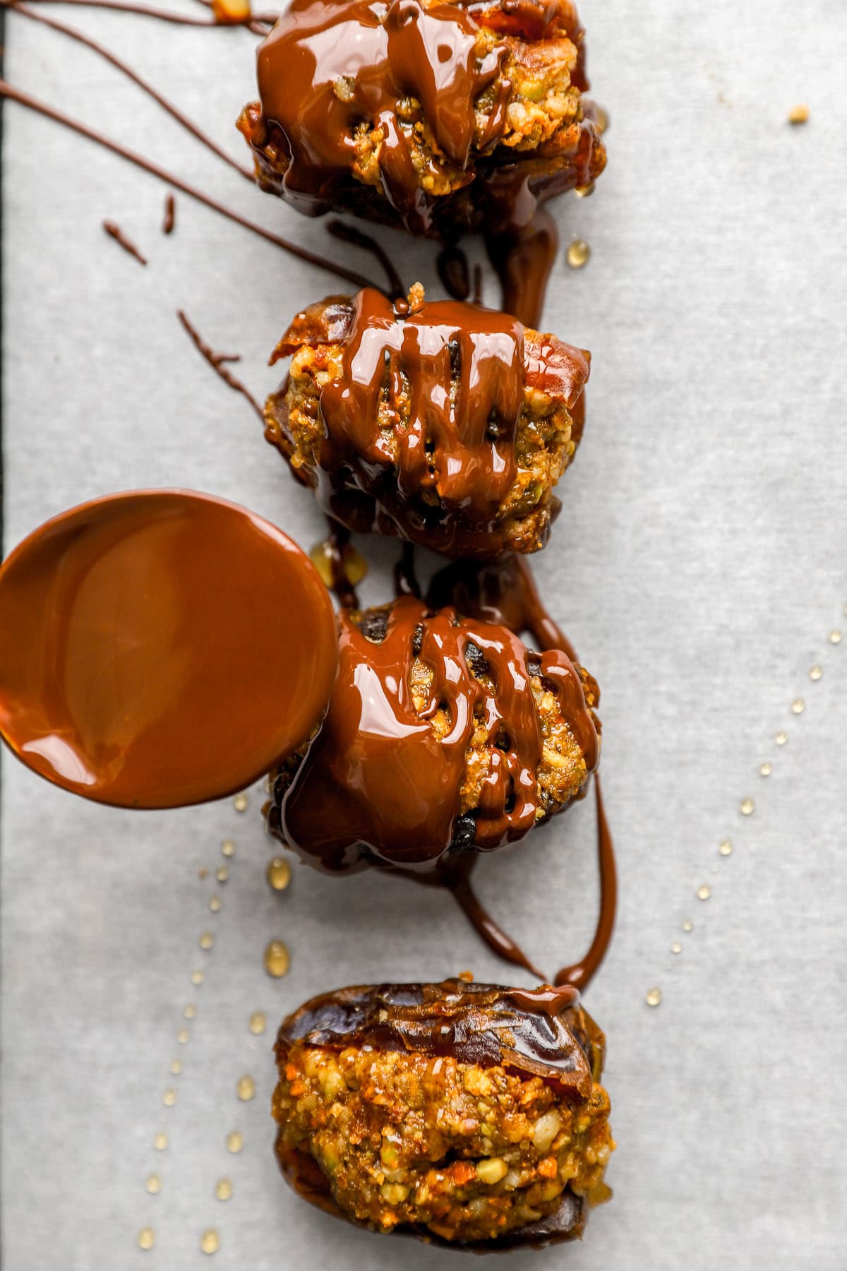 Melted chocolate being drizzled over baklava stuffed dates.