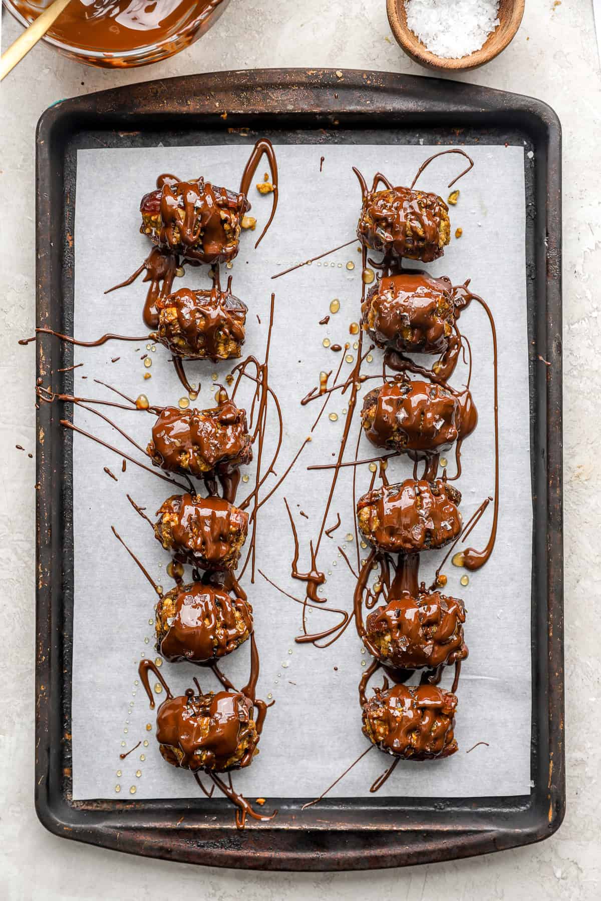 Chocolate covered baklava stuffed dates on a parchment paper lined baking sheet.