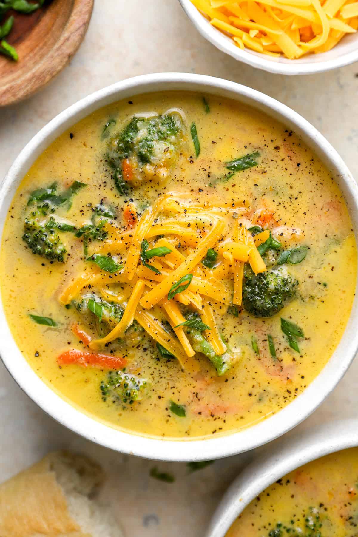A bowl of healthy broccoli cheddar soup topped with shredded cheese. 