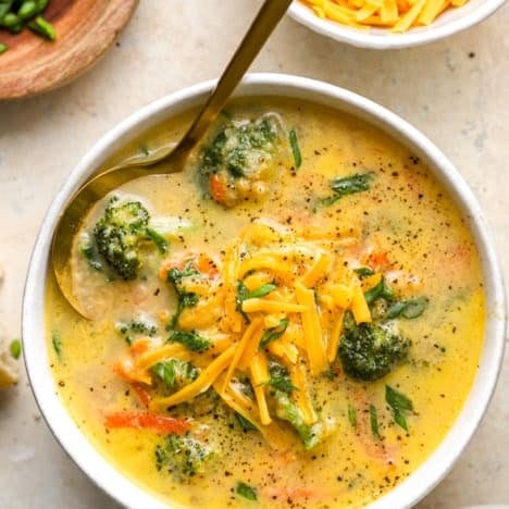 A bowl of broccoli cheddar soup with a spoon sticking out.