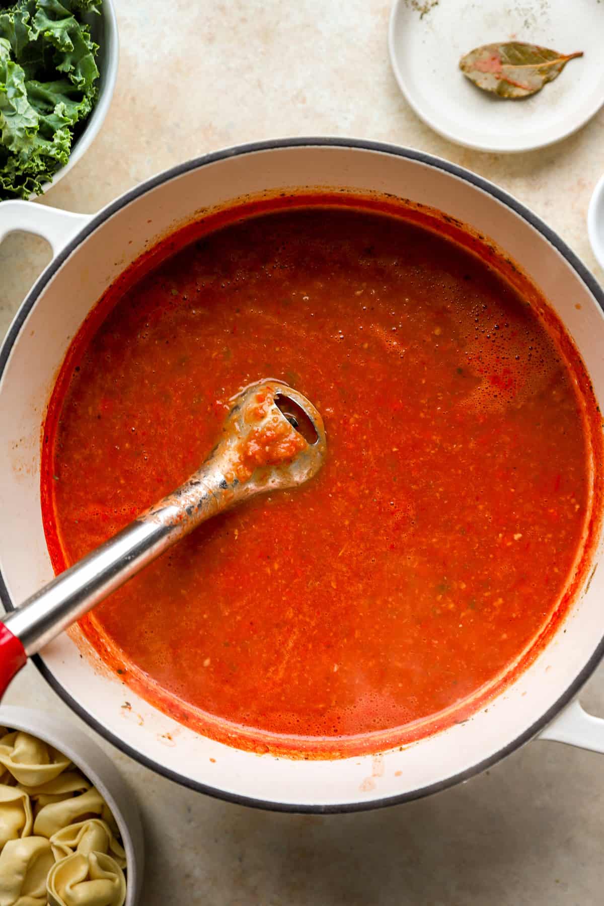 An immersion blender blending tortellini soup. 