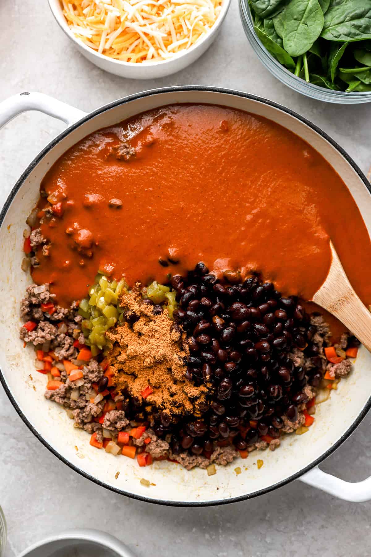Veggies, ground beef, black beans, spices, and enchilada sauce in a skillet. 