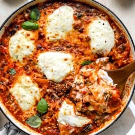 A pot of skillet lasagna with a wooden spoon sticking out.