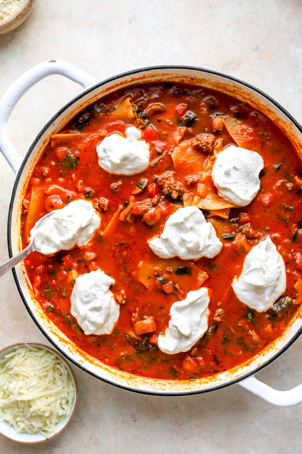 Ricotta dolloped over a skillet of lasagna.