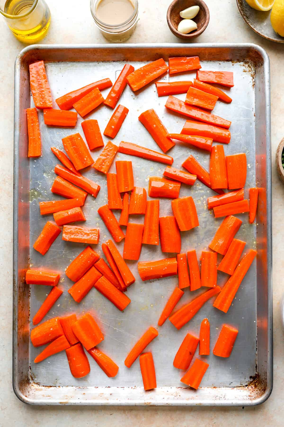 Raw carrot pieces on a rimmed baking sheet.