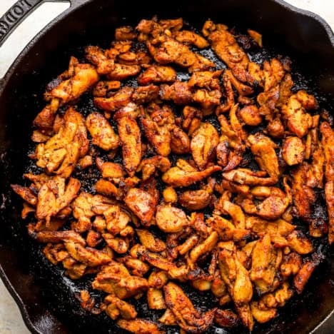 Chicken shawarma pieces cooking in a skillet.