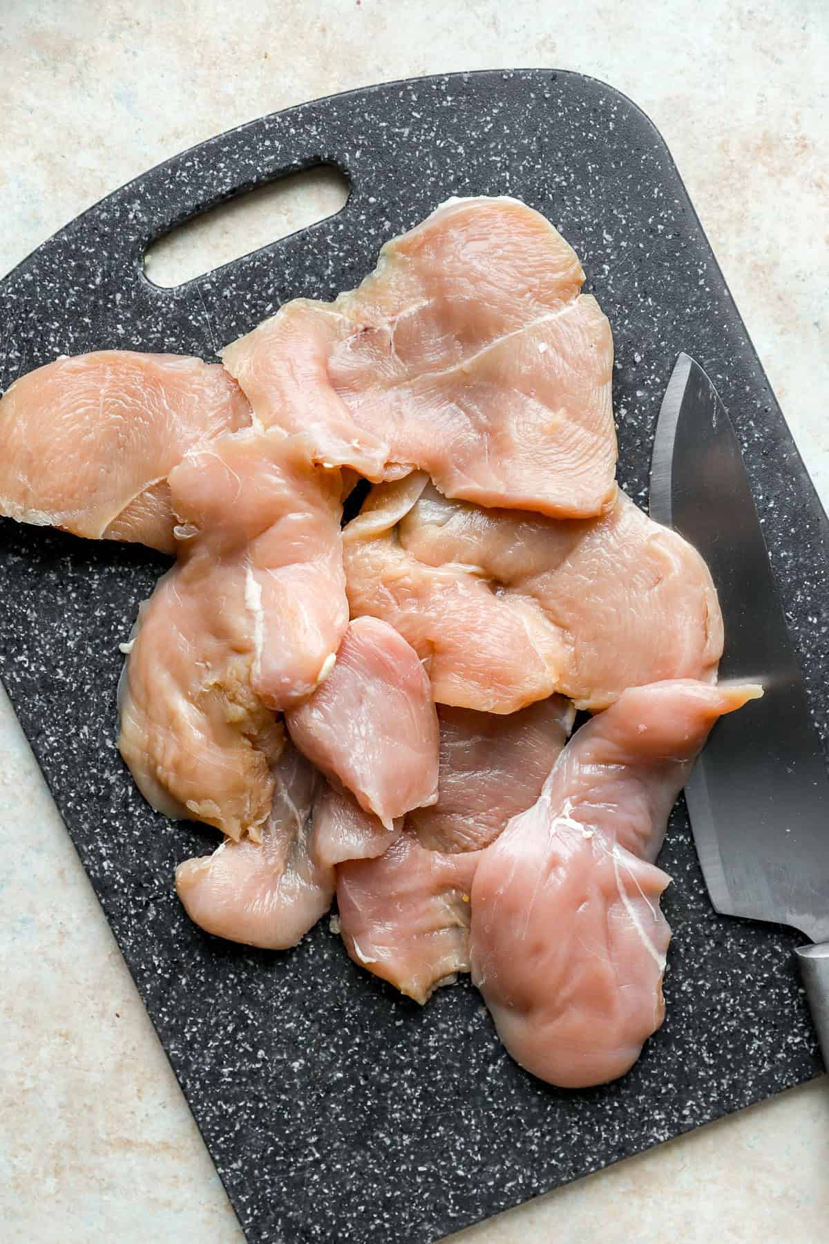 Raw chicken breast cutlets on a cutting board.