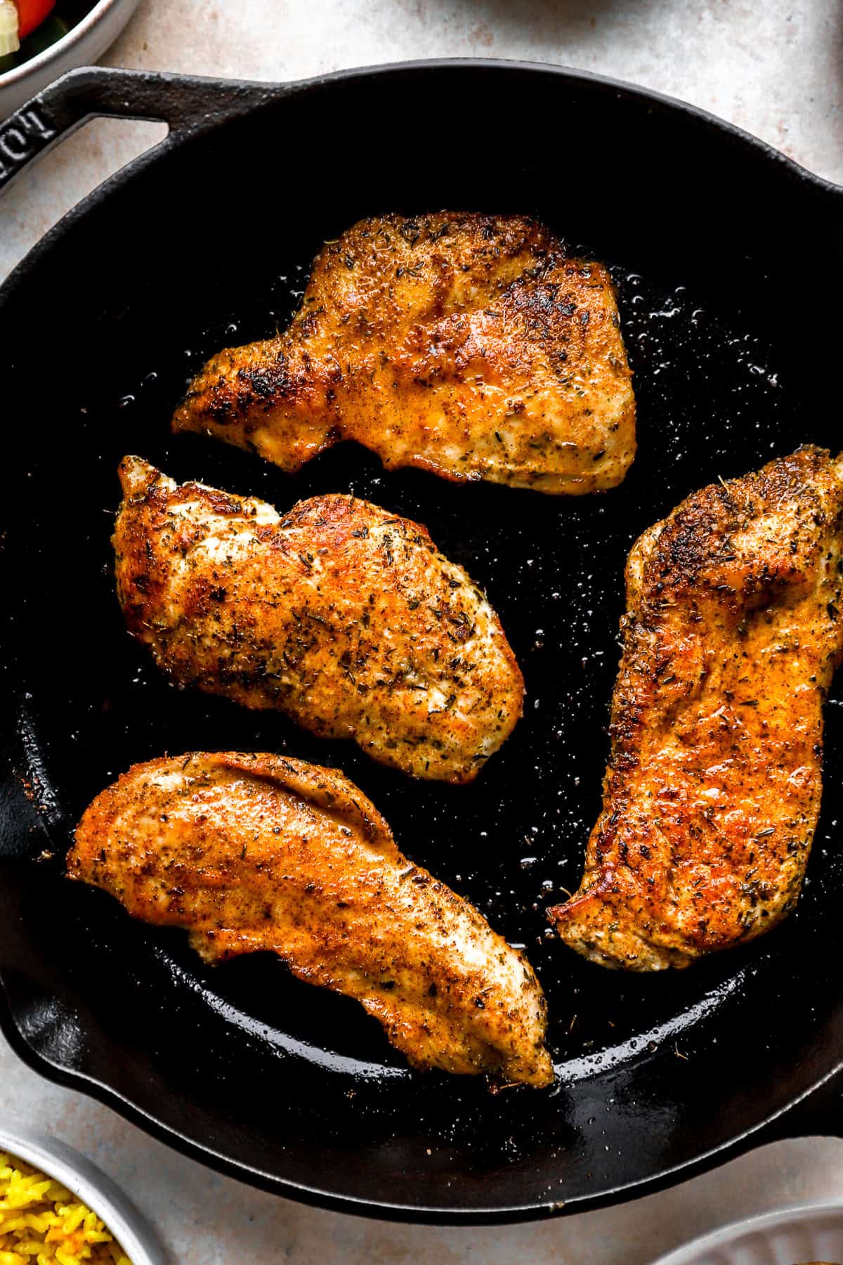 Chicken breasts searing in a cast iron skillet.
