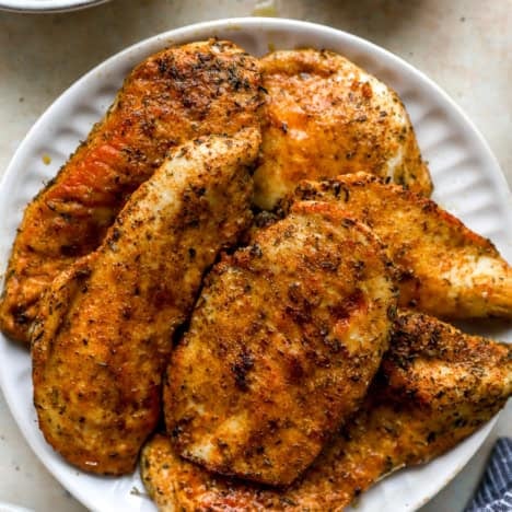 A white plate of cooked skillet chicken cutlets.