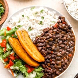 A bowl of Costa Rican Instant Pot black beans with fresh veggies, rice, and plantains.
