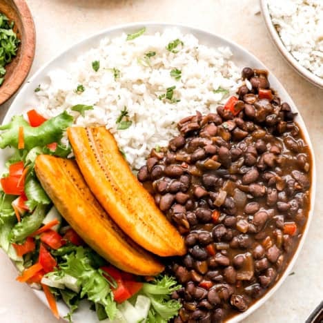 A bowl of Costa Rican Instant Pot black beans with fresh veggies, rice, and plantains.