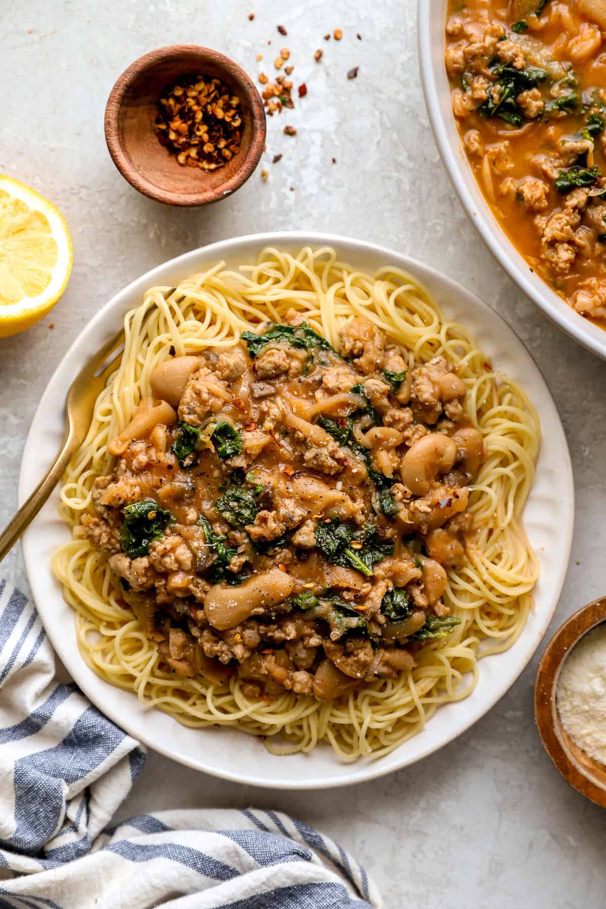 Sausage butter beans served over angel hair pasta on a plate. 