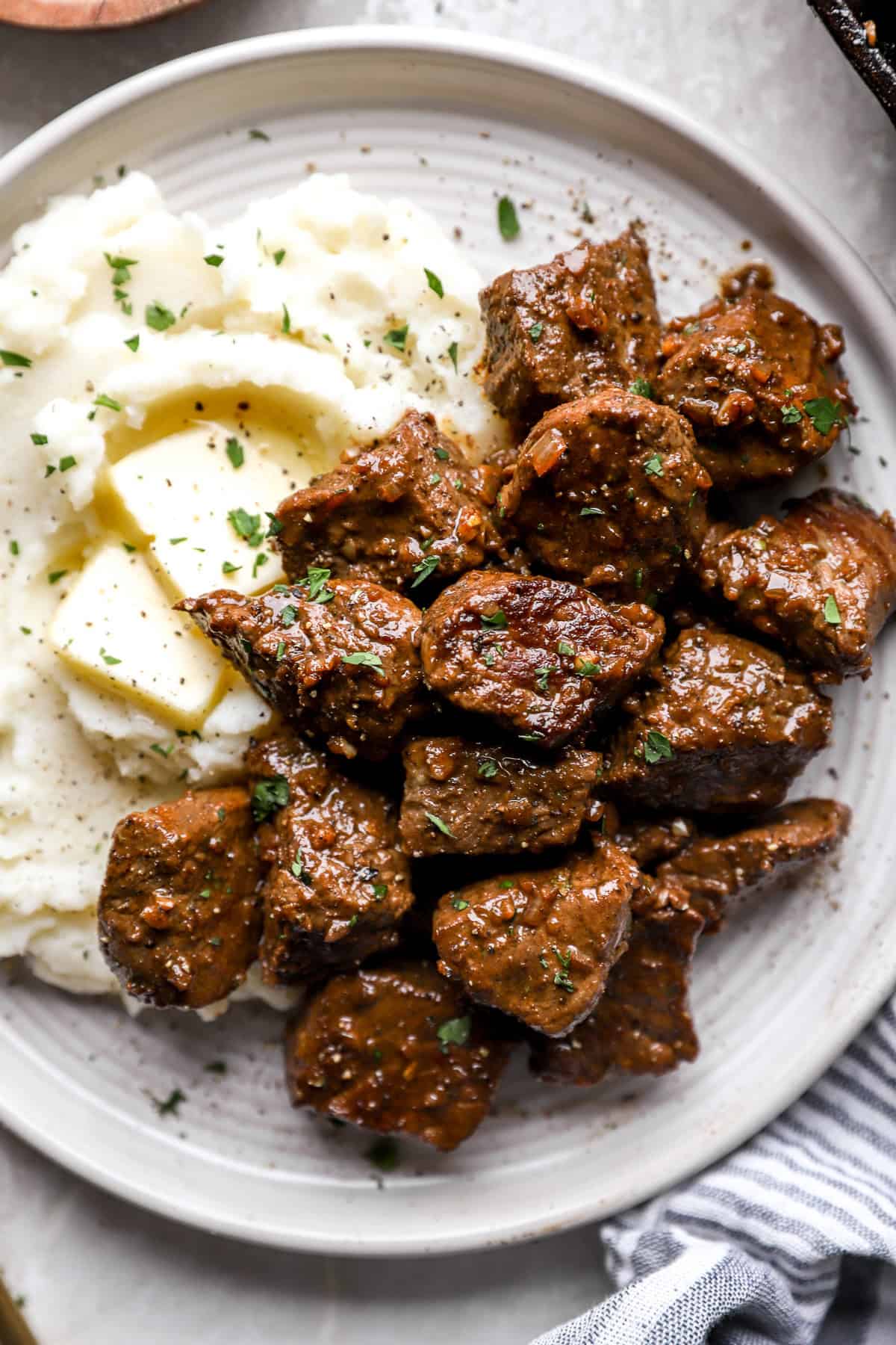 A plate of mashed potatoes and garlic butter steak bites.