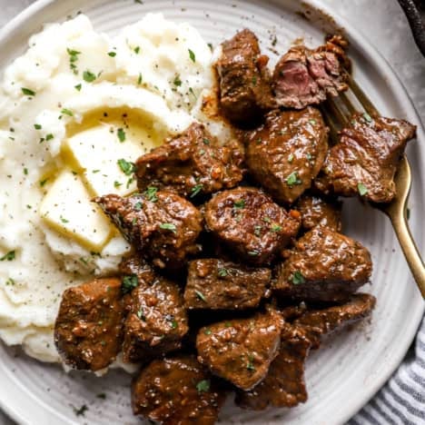 A plate of garlic butter steak bites with mashed potatoes.