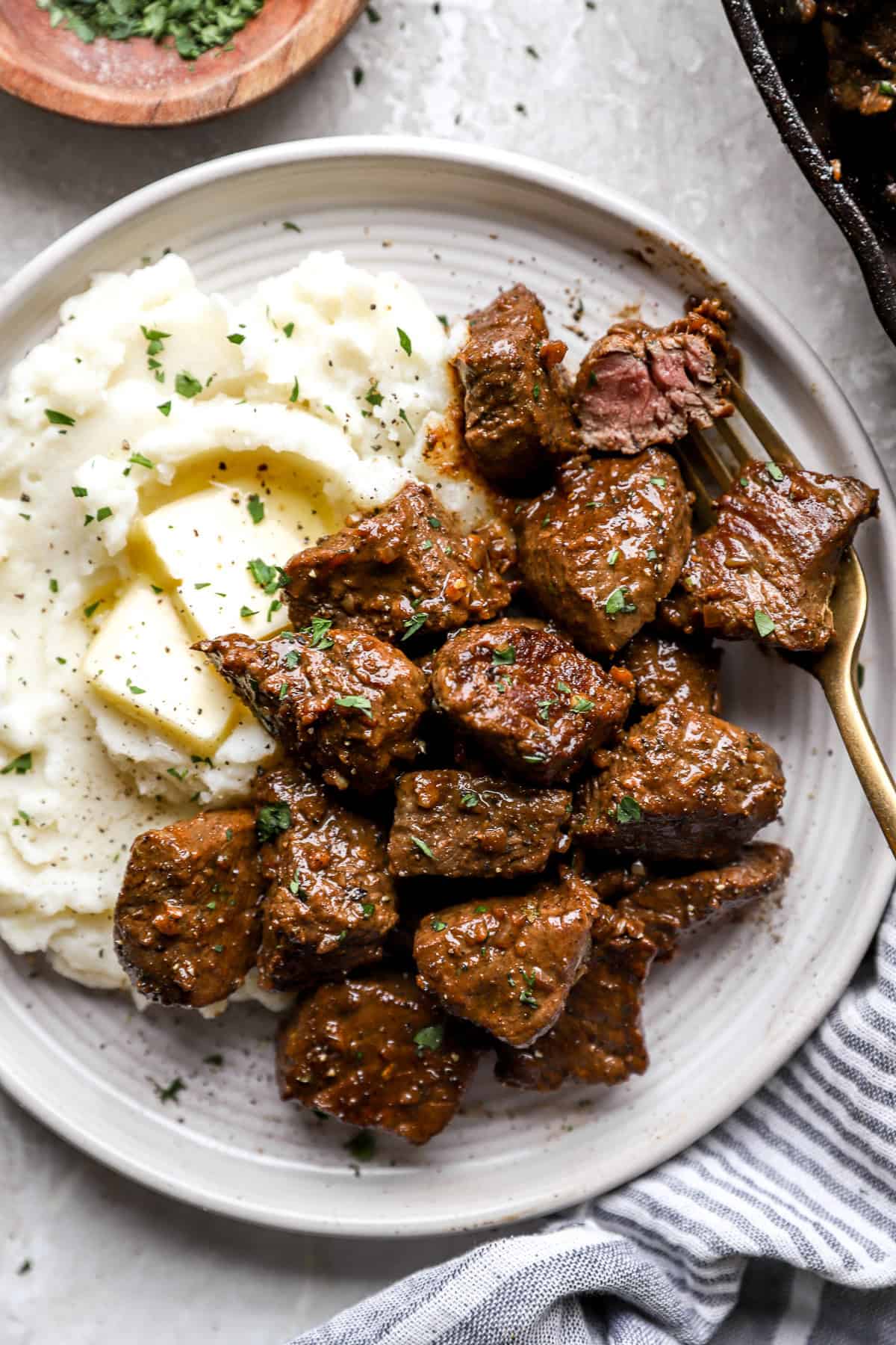 A plate of garlic butter steak bites with mashed potatoes.