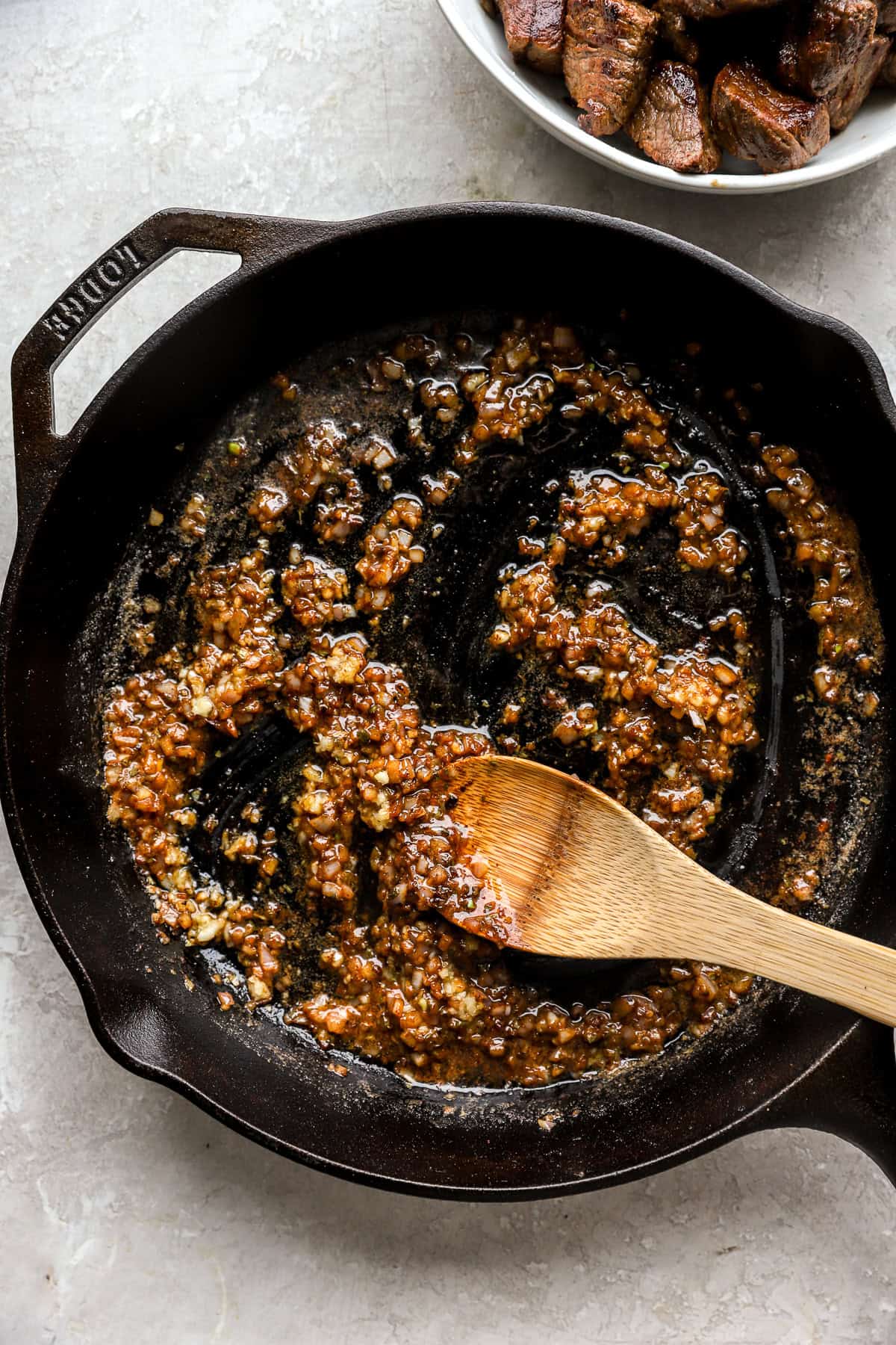 Garlic and shallots cooking in melted butter in a cast iron skillet.