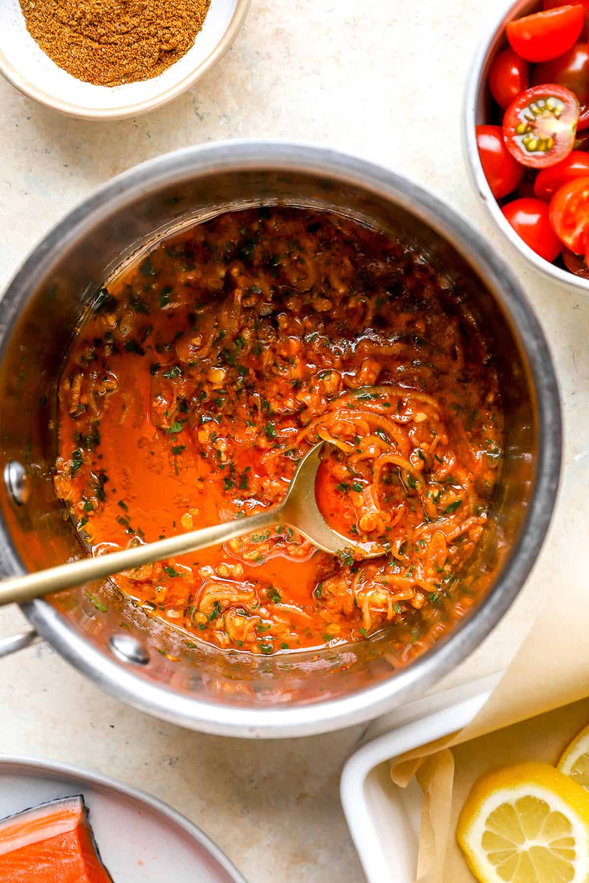 Tomato garlic paste in a pot with a spoon sticking out.