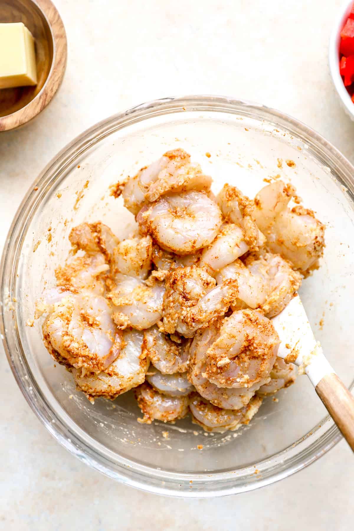 Raw shrimp in a bowl coated with garlic paste.
