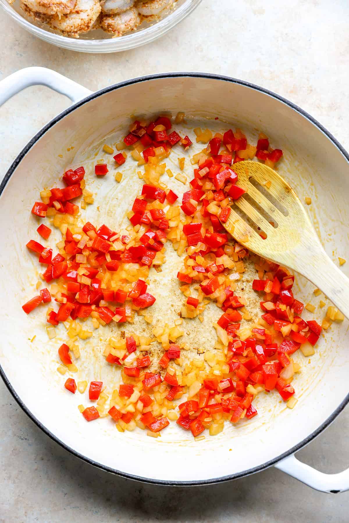 Peppers and onions sautéing in a skillet.