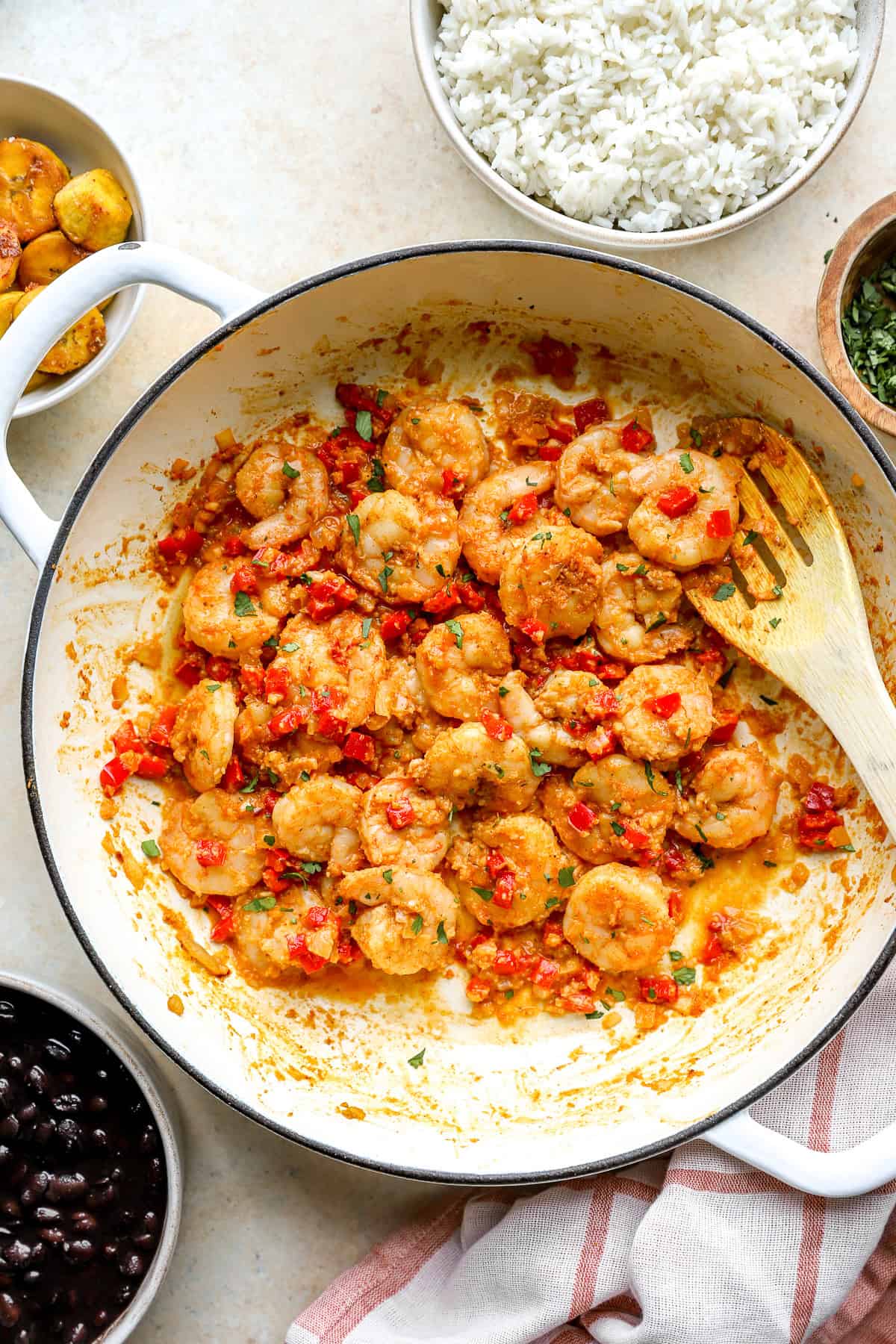Skillet garlic shrimp in a skillet with peppers and onions, a wooden spoon sticking out.