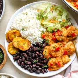 A bowl of Costa Rica garlic shrimp with rice, beans, plantains, and salad.