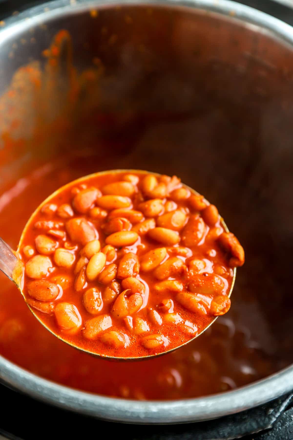 A ladle of Instant Pot pinto beans being lifted from an Instant Pot.