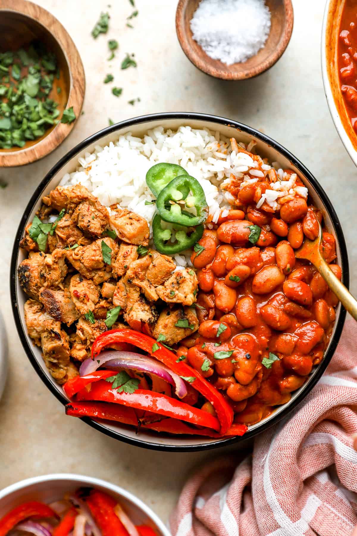A bowl of Instant Pot pinto beans, peppers, meat, and rice topped with jalapeño slices.