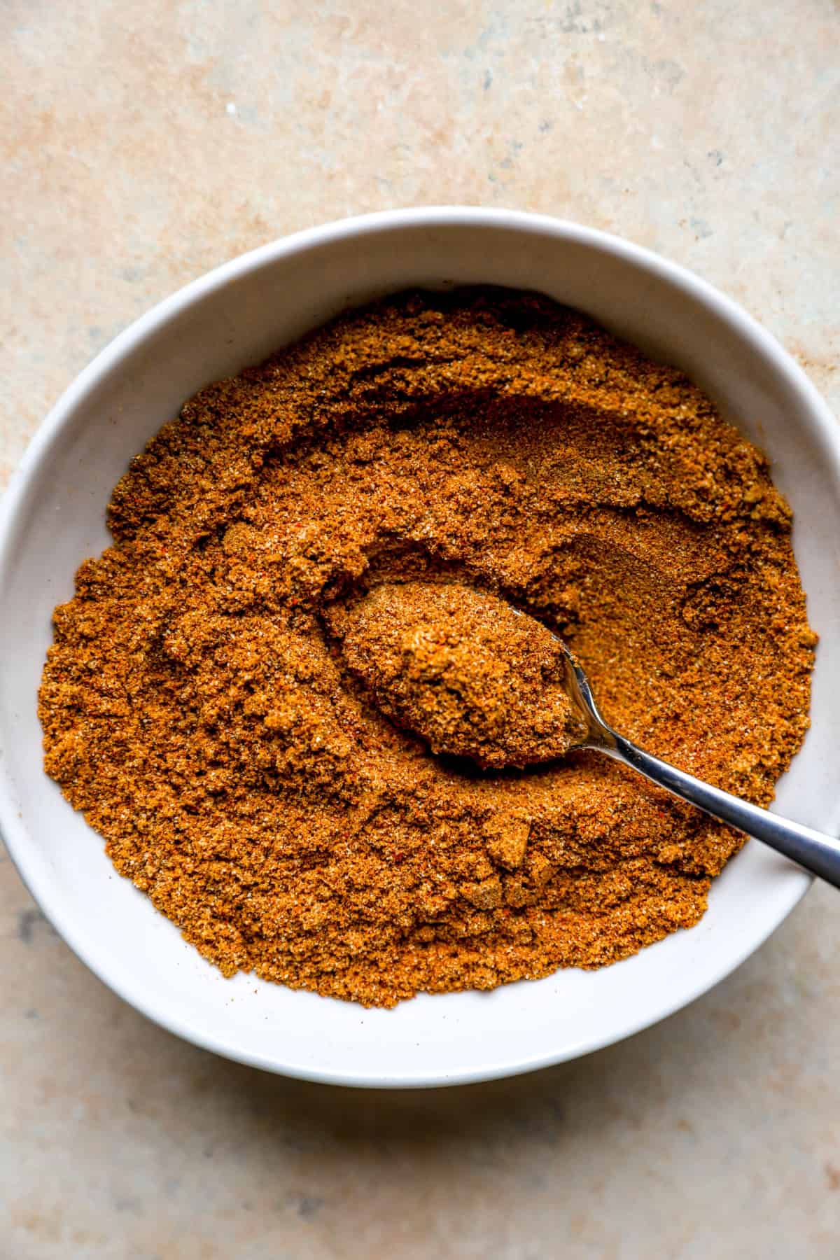 A bowl of homemade shawarma seasoning with a spoon sticking out.