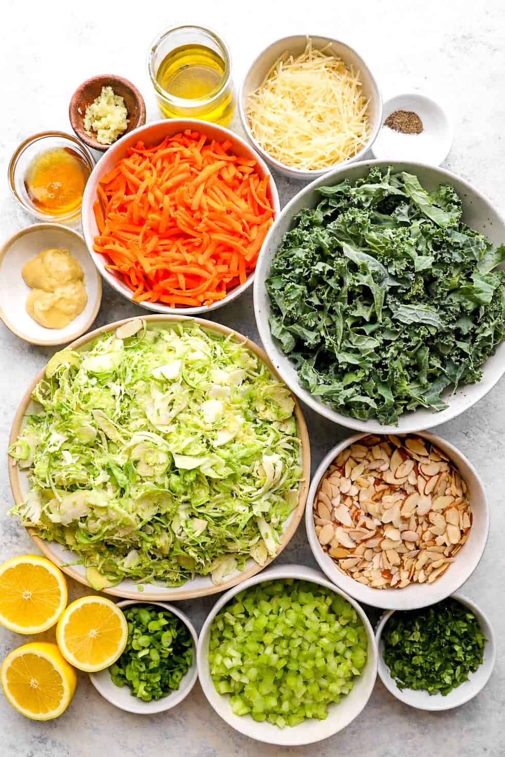 Bowls of fresh veggies, nuts, spices, etc. to make summer Brussels sprouts and kale slaw.