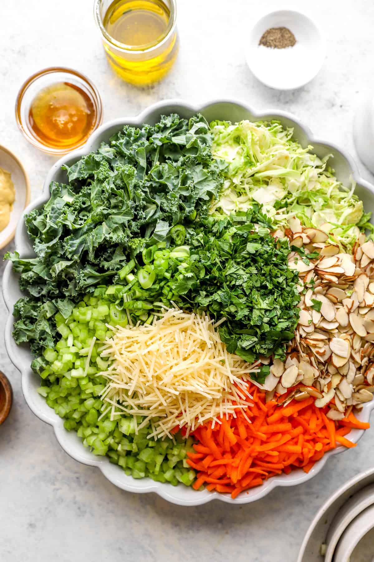 A bowl of fresh veggies, sliced almonds, and shredded Parmesan cheese.