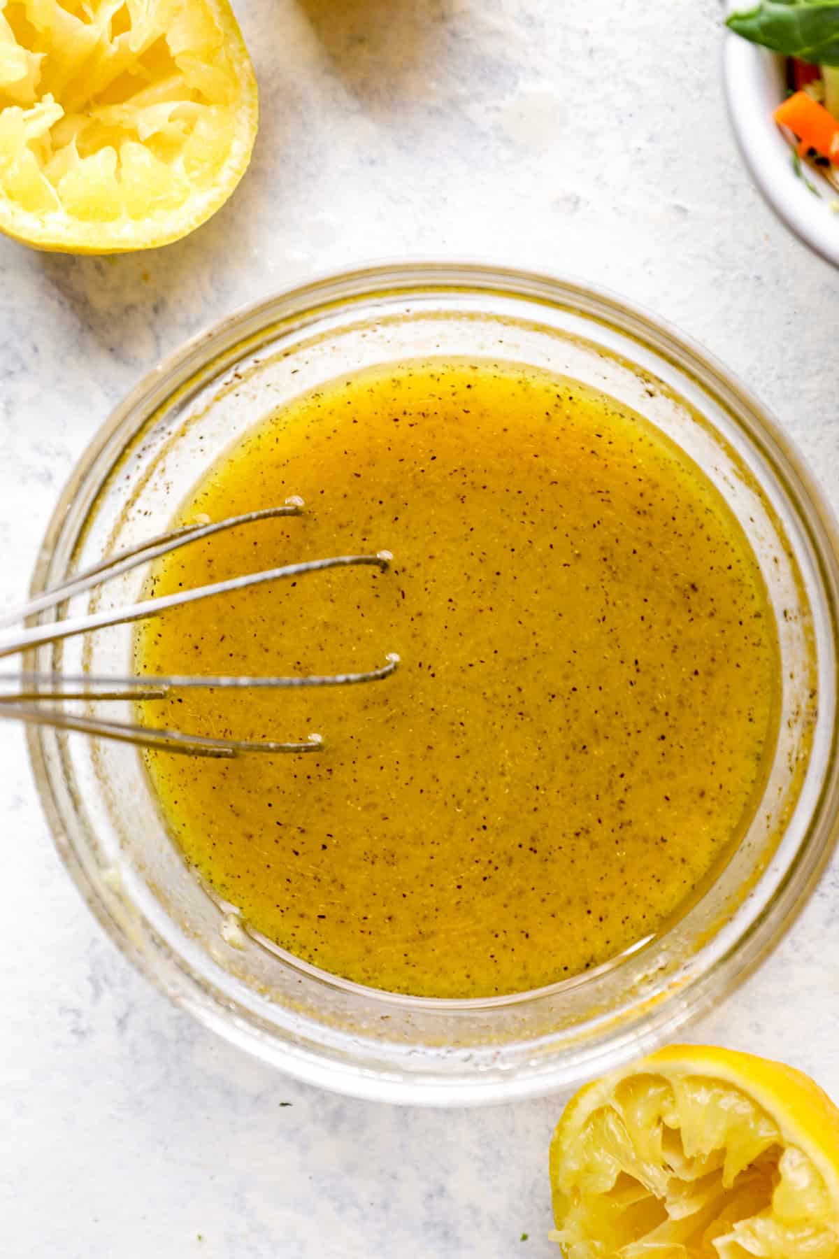 A bowl of lemon Dijon vinaigrette with a whisk sticking out.