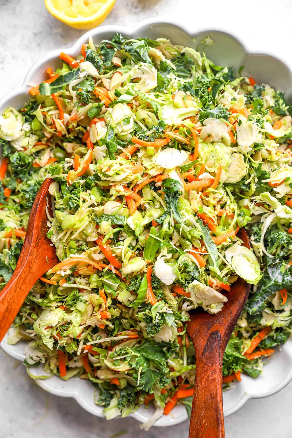 Summer Brussels sprouts and kale slaw with wooden serving spoons sticking out.