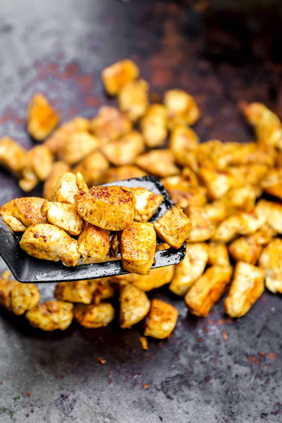 A spatula lifting hibachi chicken from a skillet.