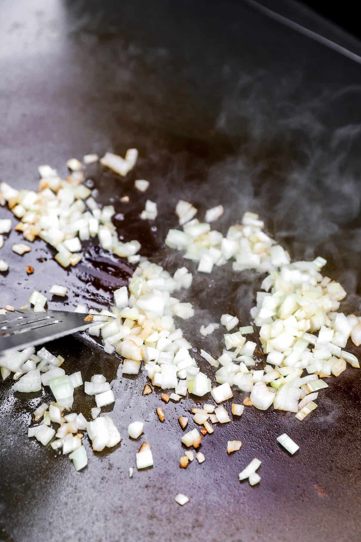 Onions sautรฉing in a skillet.