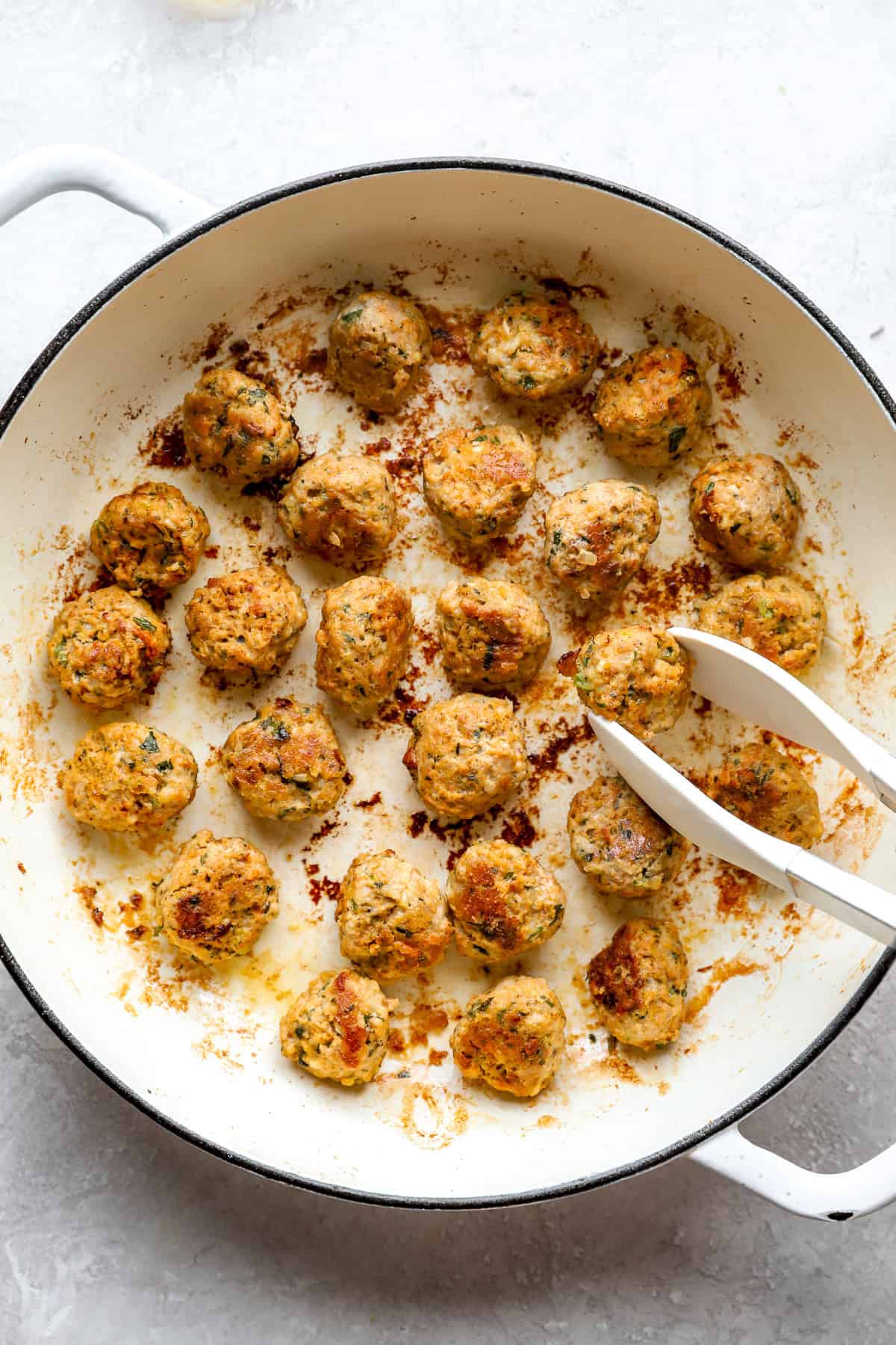 Honey garlic chicken meatballs searing in a skillet.
