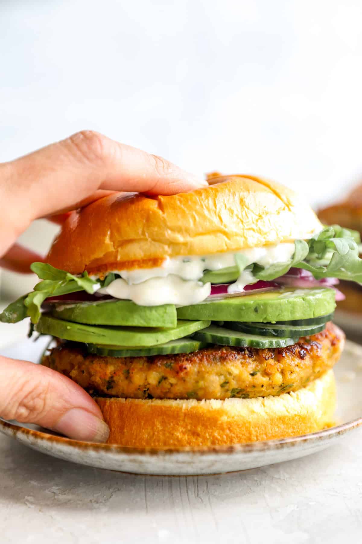 A hand holding an herby ground chicken burger.
