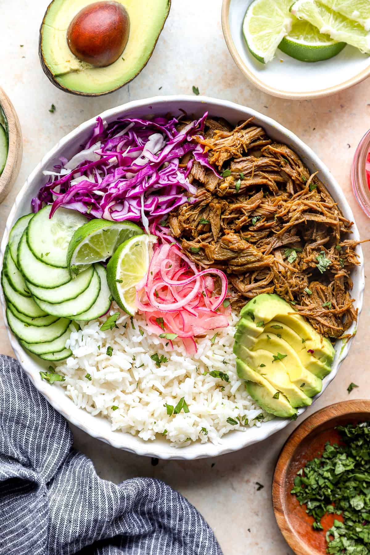 A bowl of rice, cucumbers, pickled red onion, cabbage, shredded beef, and avocado.