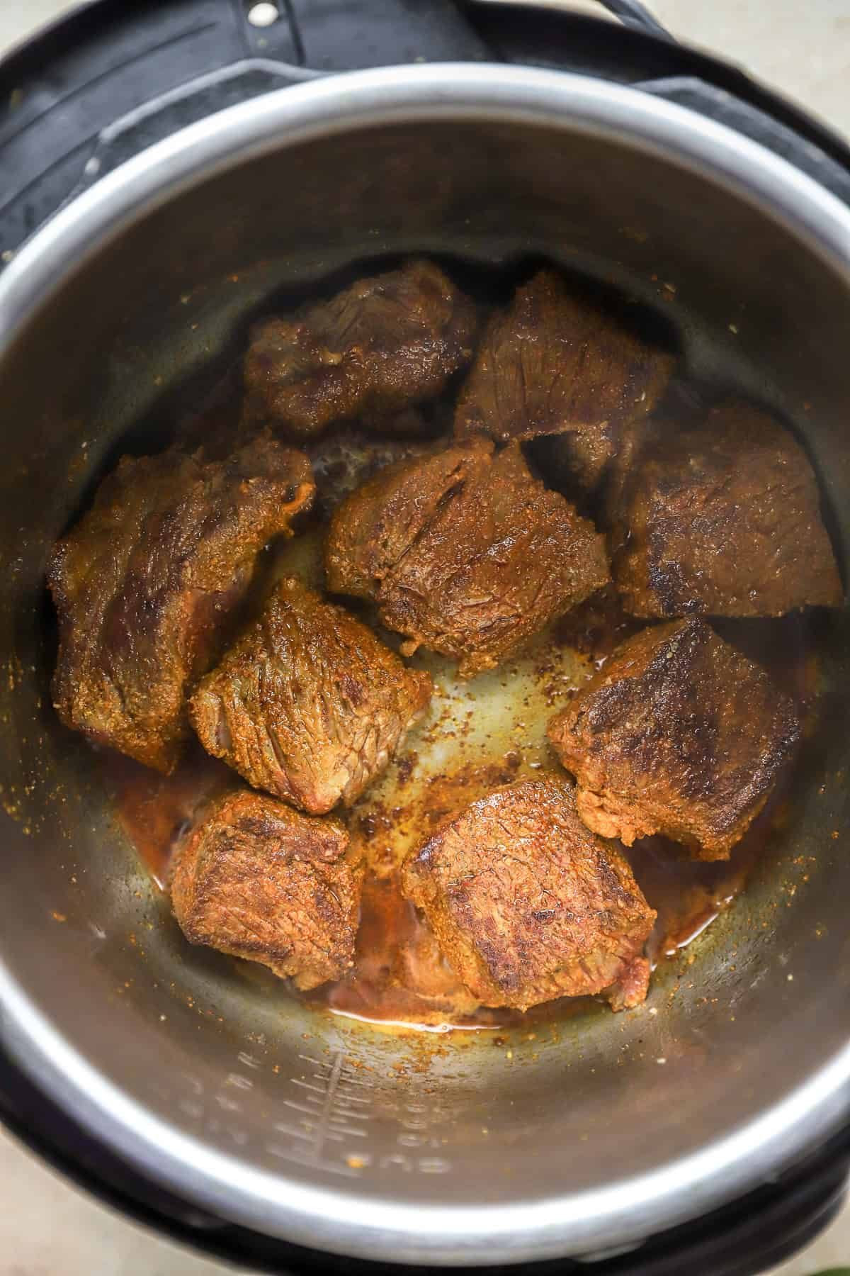 Chuck roast pieces searing in oil.