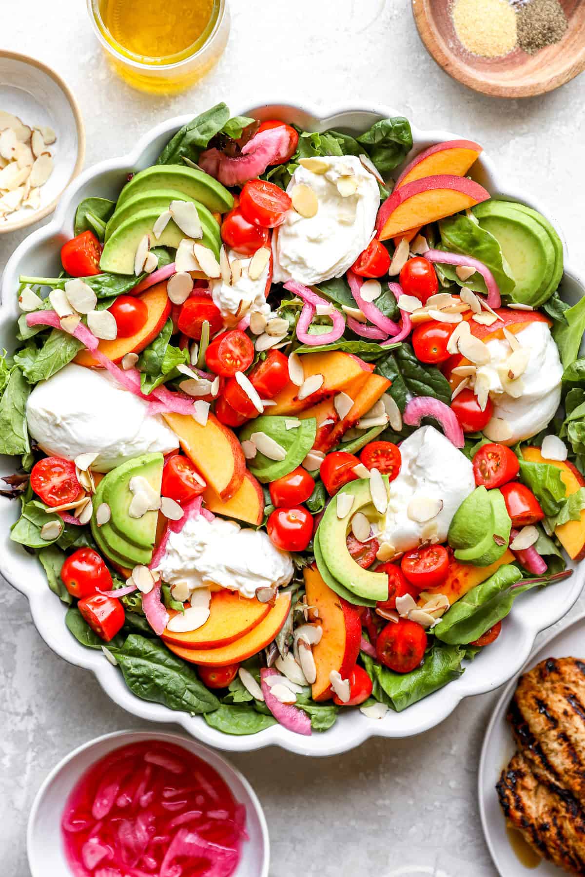 Ingredients for a peach burrata salad being combined in a bowl.