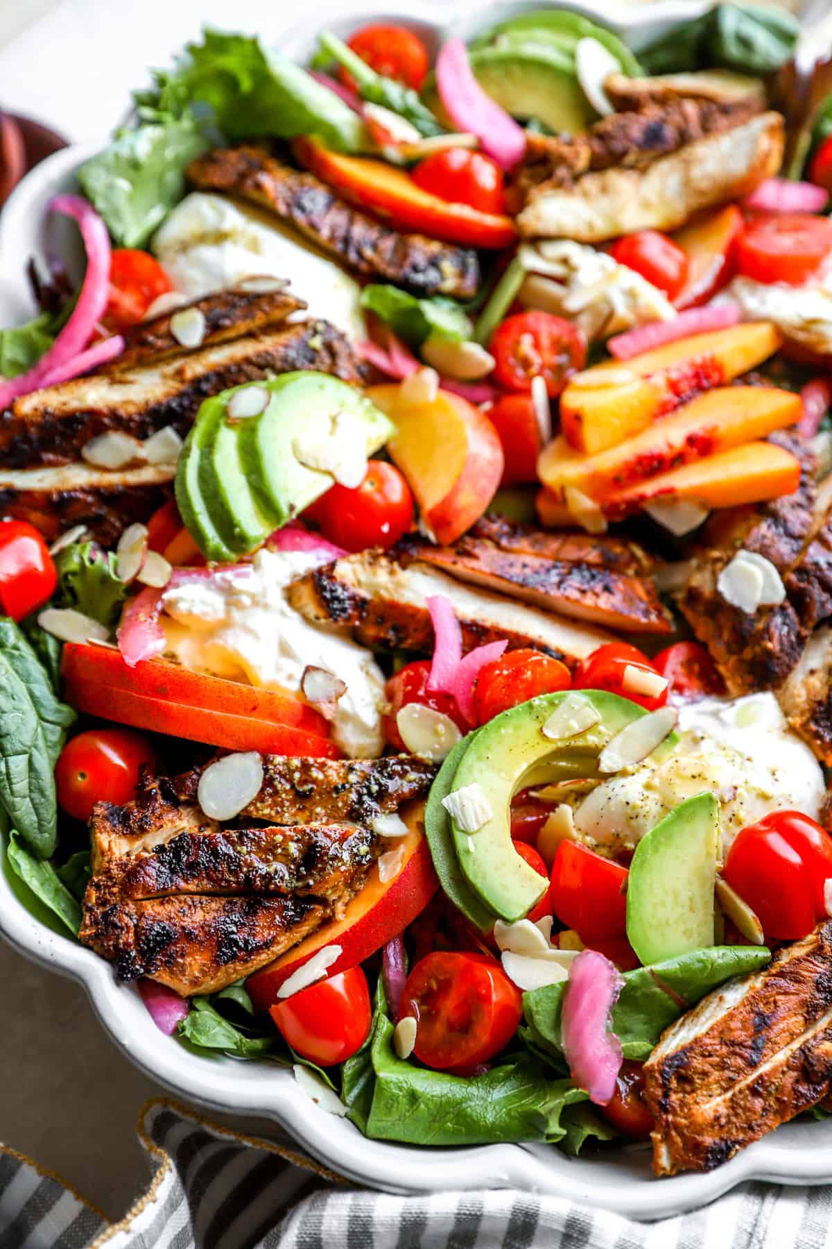 A peach burrata salad tossed with dressing.