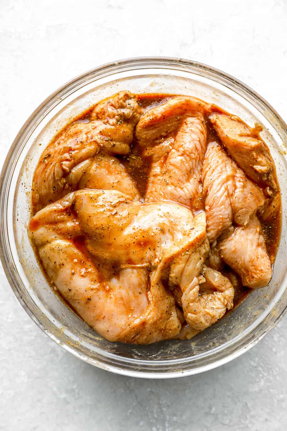 Raw chicken breasts marinating in a balsamic mixture.