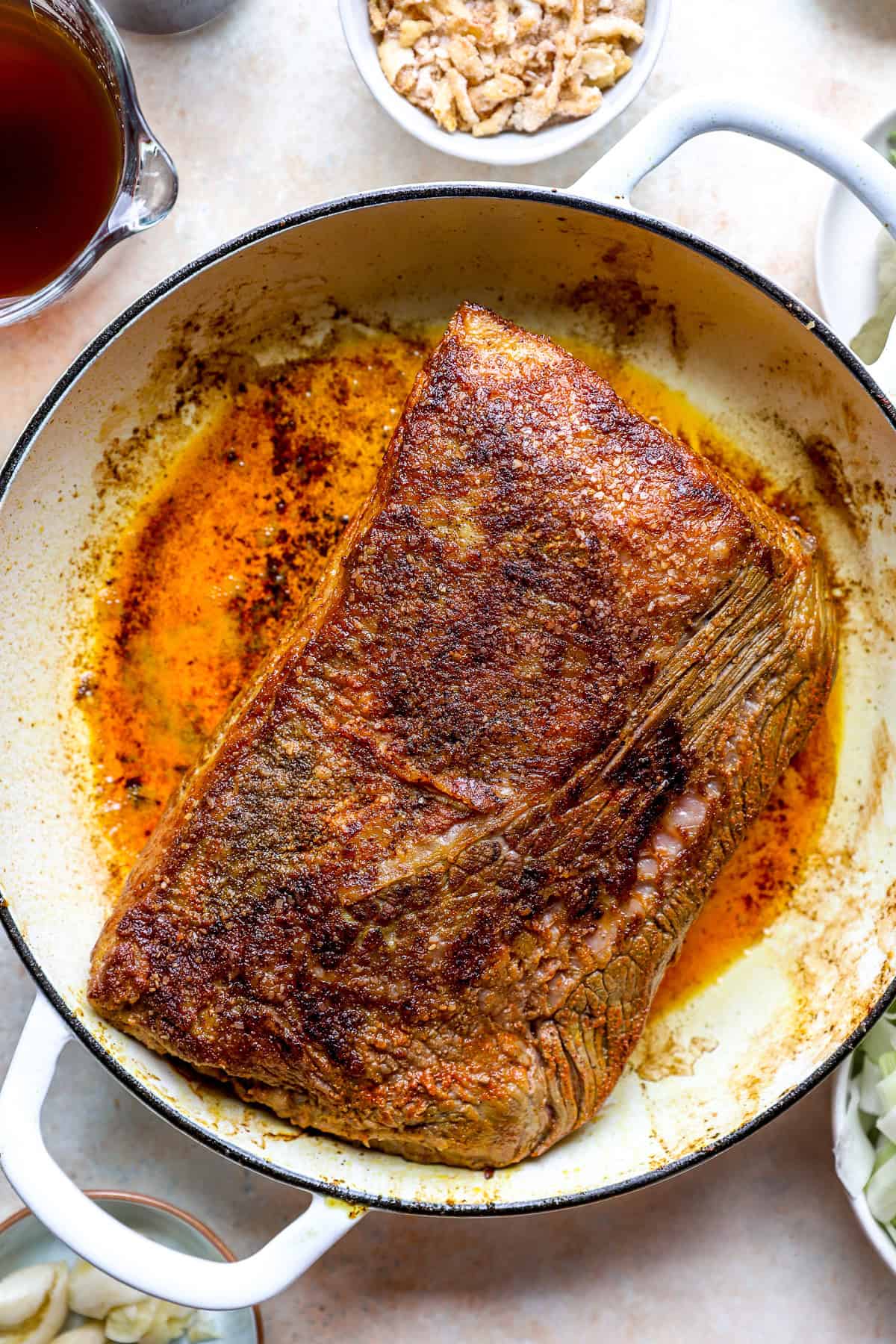 A seasoned brisket searing in a pot.