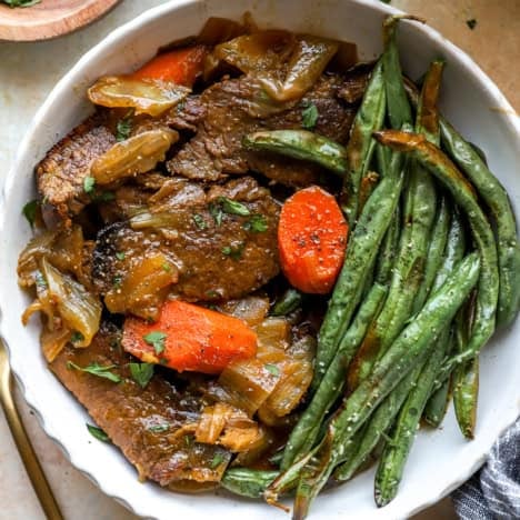 A plate of braised brisket with carrots and green beans.