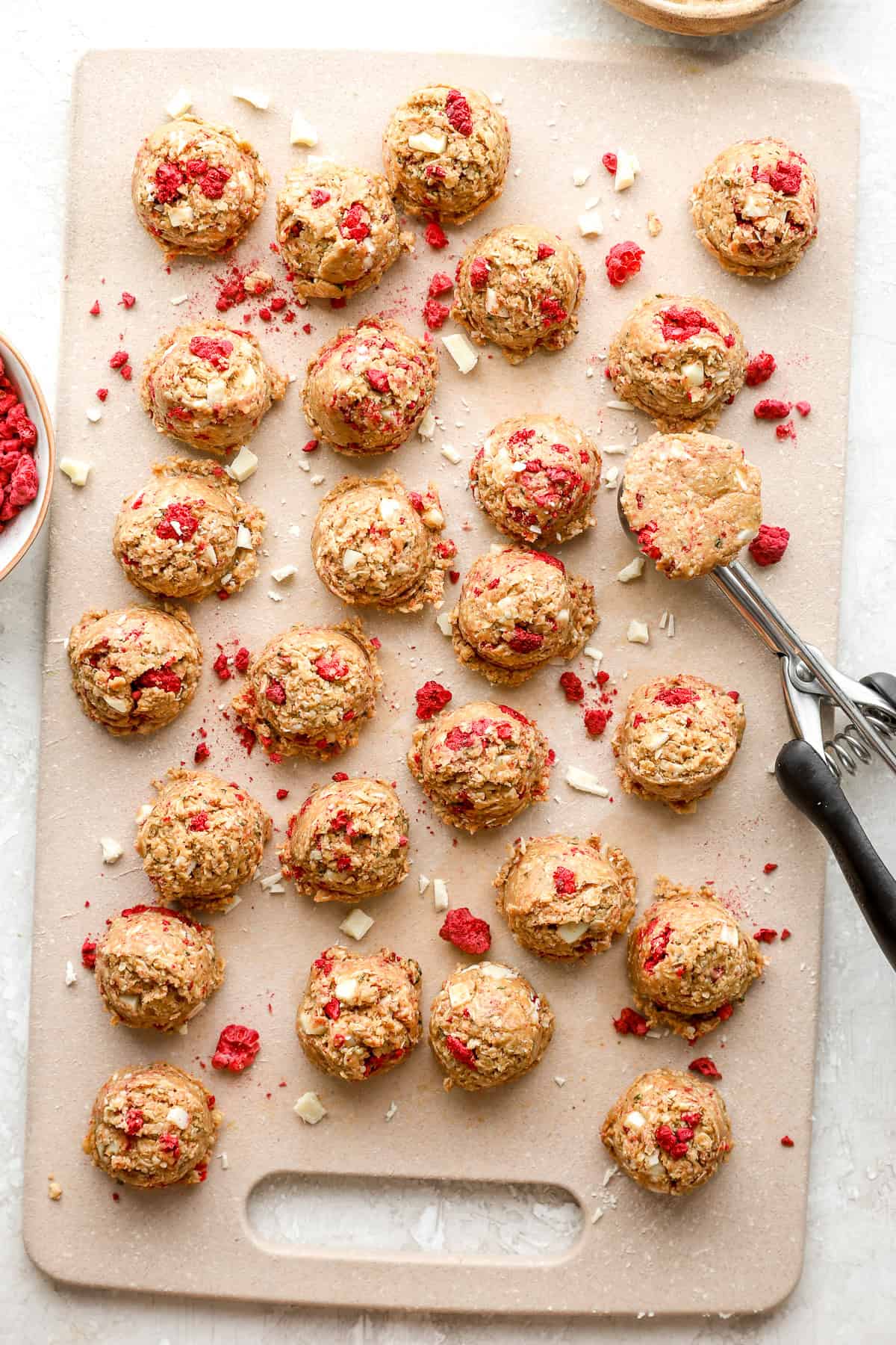 A cooking scoop being used to portion raspberry white chocolate protein balls.