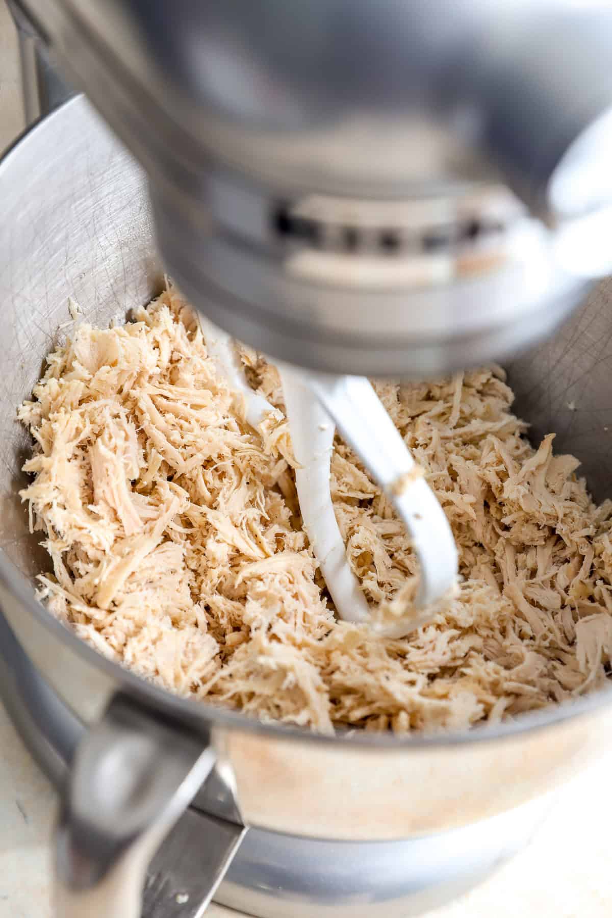 A stand mixer shredding chicken.