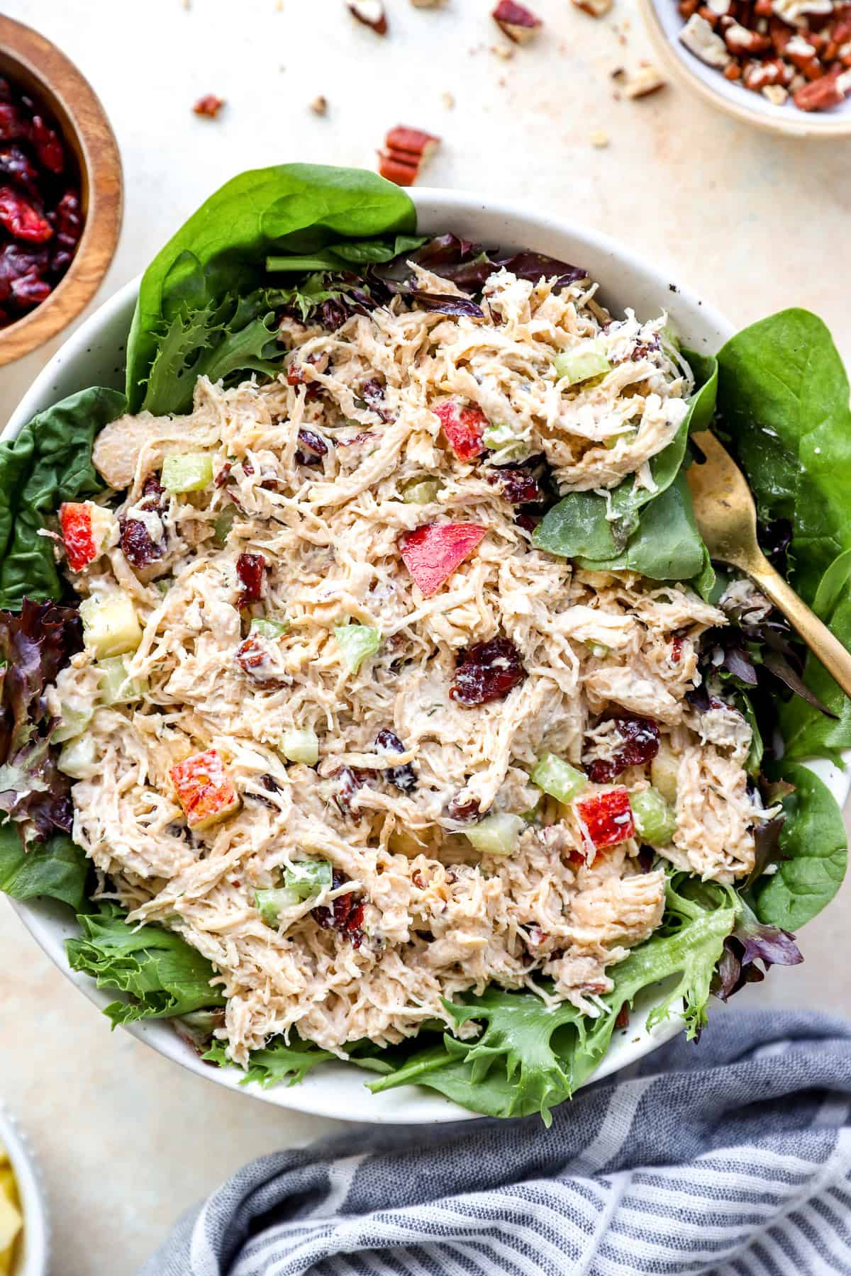 Harvest chicken salad over a bed of greens in a bowl, a fork on the side.