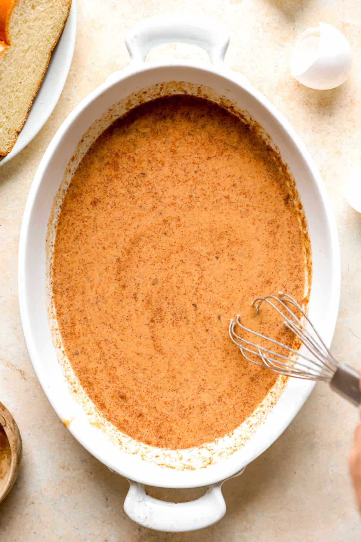 Pumpkin custard being whisked in an oval dish.