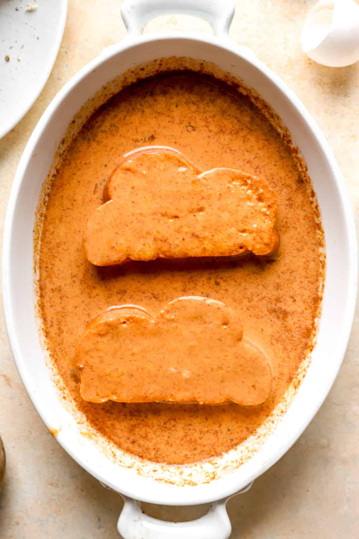 Bread pieces being dipped in pumpkin custard.