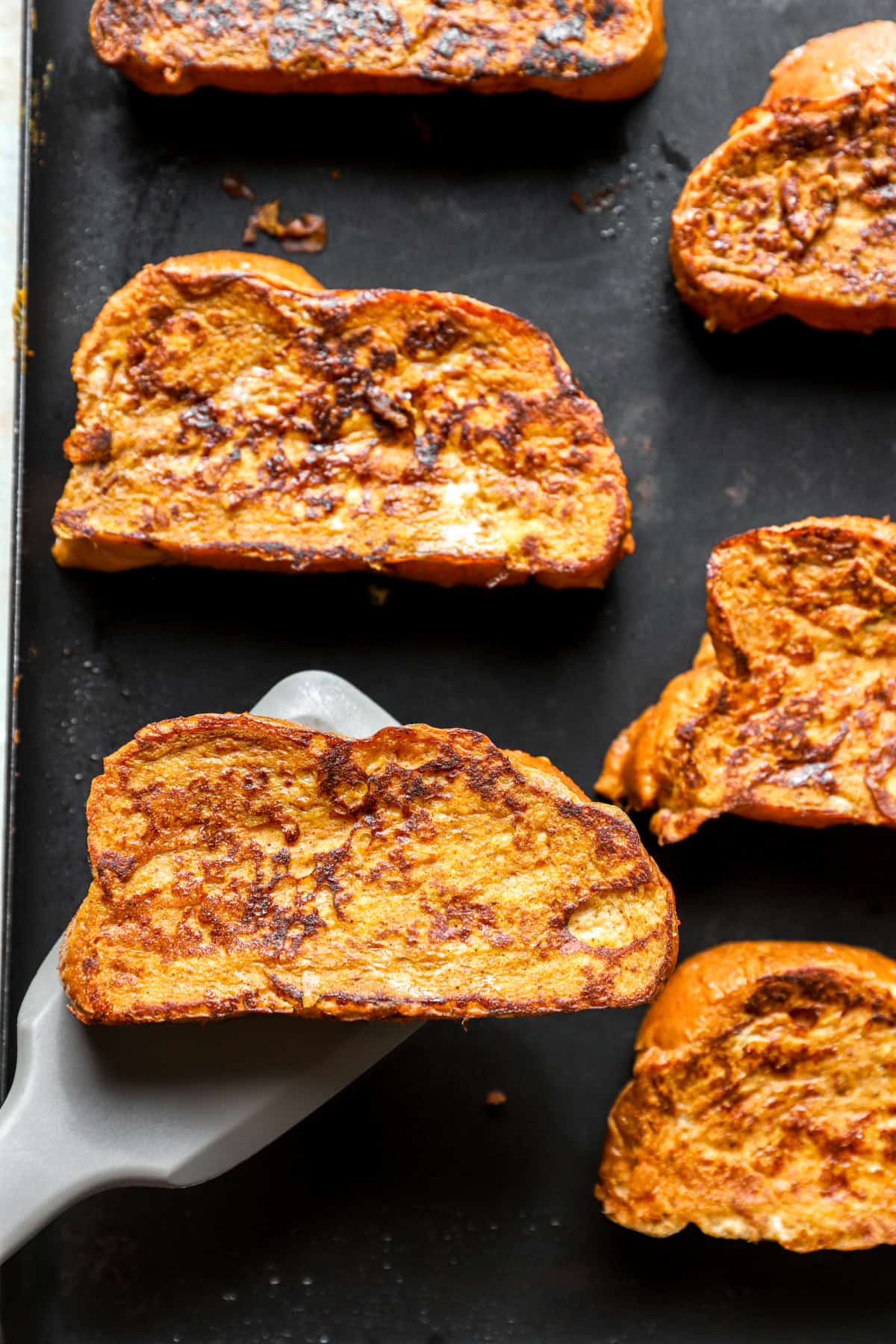 Pumpkin French toast cooking on a griddle.